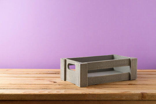 Empty wooden box on table over purple wall background. Autumn harvest concept for mock up design