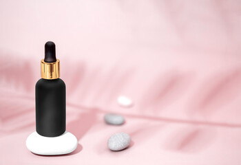 A black matte bottle with a pipette for serum, vegetable emulsion on a pink background. Natural...