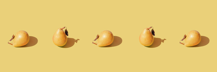 Creative composition made raw pears on pastel yellow background with shadow. Healthy food...