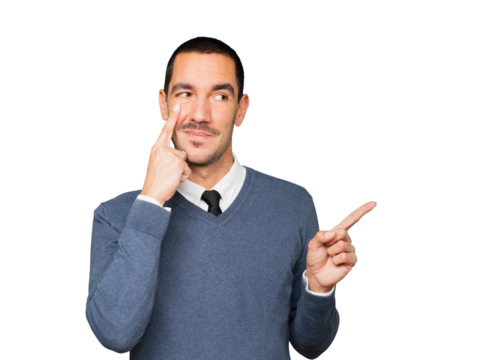 Friendly young man making a gesture of being careful with his hand pointing at his eye