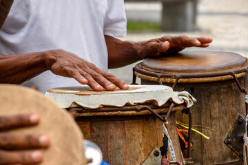 Percussionist playing a rudimentary atabaque during afro-brazilian capoeira fight presentation in...