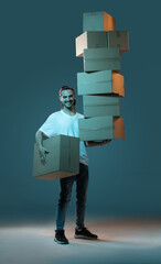 Emotional delivery guy with a lot of boxes on a dark blue background