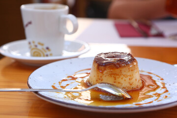  spanish flun pudding dessert closeup photo with teaspoon and cup of coffee on the background