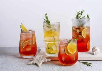 Four colorful Christmas cocktails in glasses on white table. Assortment of fresh holiday drinks. Strawberry Mojito, orange punch cocktail, tropical mule.