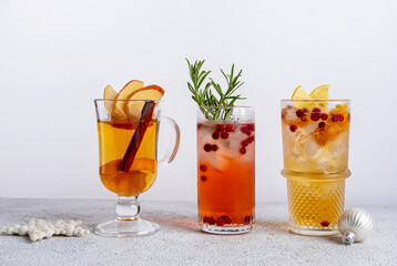 Three colorful Christmas cocktails in glasses on white table. Assortment of fresh holiday drinks. Red sangria cocktails, orange punch cocktail, tropical mule.