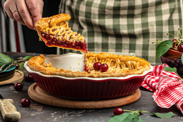 Woman with tasty cherry pie. One piece on a plate and the whole homemade cherry pie