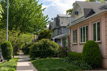 Row of Beautiful Neighborhood Homes with Green Grass along a Sidewalk in Midwood Brooklyn of New...