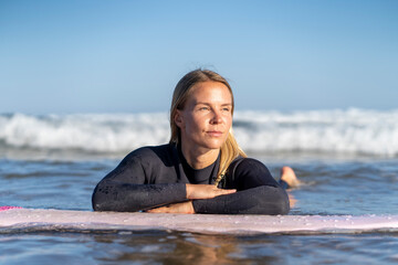 Surfer girl in the water looking at the waves. Female surfer woman