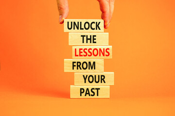 Lessons from your past symbol. Concept words Unlock the lessons from your past on wooden blocks. Bussinesman hand. Beautiful orange background. Business and lessons from your past concept. Copy space.