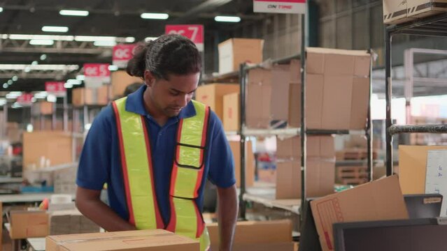 Two asian warehouse worker working checking package products in warehouse, logistic. While staff used laser barcode scanner on cardboard box, distribution center, placement in storage for shipping.
