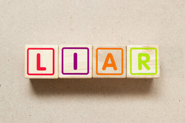 Color letter block in word liar on wood background