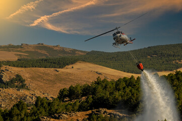 Helicopter against fires, carrying out a discharge of water.