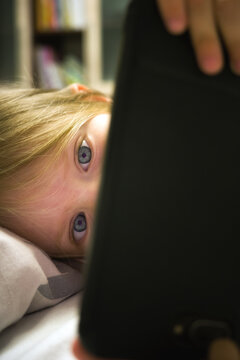Small kidl looking on smartphone screen. Child mobile phone addiction
