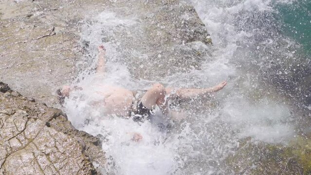 Sea waves in slow motion.
The waves of the sea hit the young model man lying by the sea.
