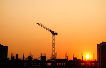 Obraz premium Sunset over Building construction in the city. Crane and structure silhouettes