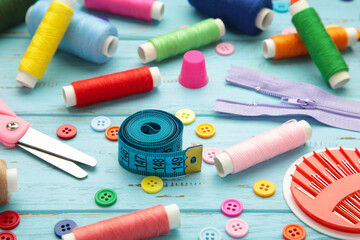Sewing supplies on blue background: sewing thread, scissors, a large spool of thread, pieces of...