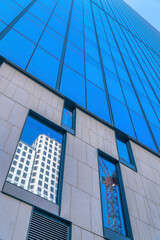 Obraz premium Modern building exterior with glass facade reflecting a construction crane