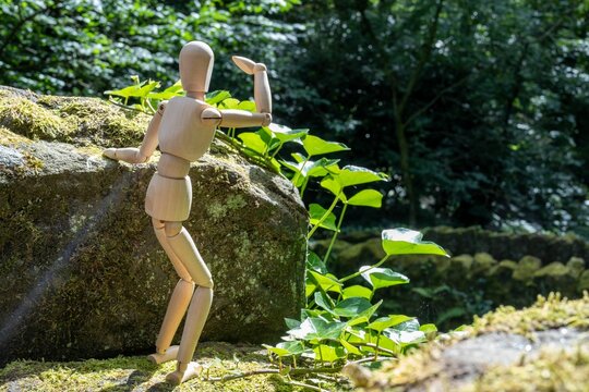 A wooden artist's figure standing, looking out over a river. Concept of a person with hope in nature
