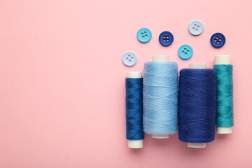 Blue cotton yarns on rolls for sewing on pink background. Space for text