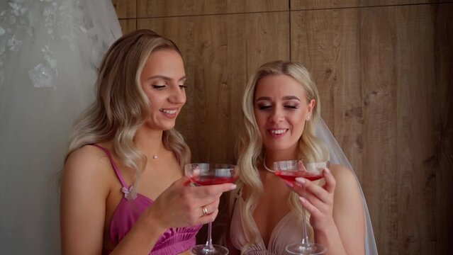 Girls having fun on wedding morning in living room. Happy caucasian young adult women smile laugh drink alcohol champagne indoors. Marriage preparations and females party in luxury apartments