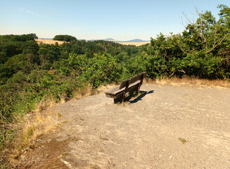 Holzbank am Rande eines Abhangs mit Blick in die Vulkaneifel bei Ochtendung im Landkreis Mayen-Koblenz vom Wanderweg Traumpfädchen Nette-Romantikpfad.