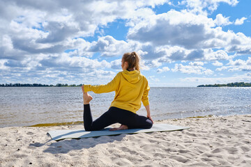Fototapeta premium Athletic girl exercising outdoors, ready to do yoga with sports training or stretching. Healthy active lifestyle. Wellness and sport concept 