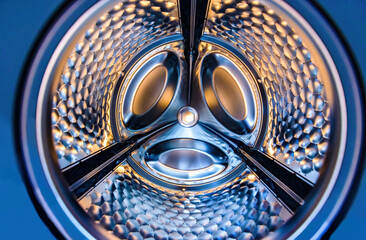 Washing machine drum interior. Perspective inside view into blue washing machine drum moving in...