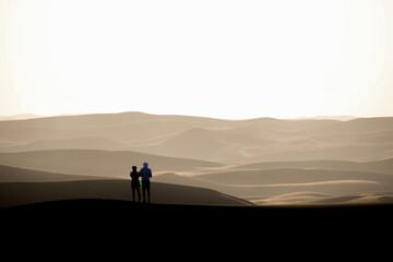Fototapeta na wymiar Couple on a sand dune in the Sahara desert