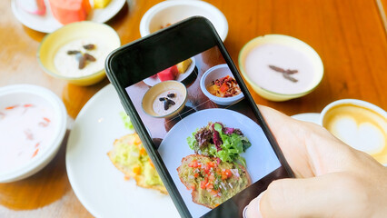 Man hand take photos of breakfast by mobile phone