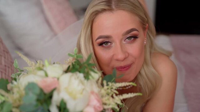Bride girl laying on bed in living room close up. Luxury young adult caucasian woman preparation to wedding. Bridal female portrait looking at camera indoors