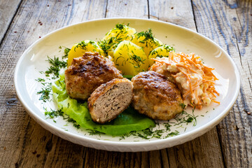 Fried meatballs with boiled potatoes and carrot salad on wooden table
