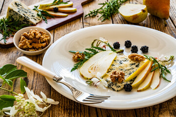 Fresh salad - blue cheese, blackberries, pear, arugula and pecan nuts on wooden background
