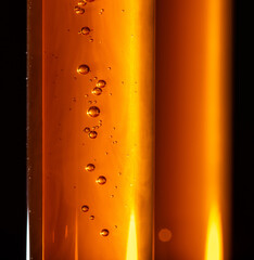 Yellow viscous liquid sunflower lecithin with bubbles in a transparent test tube on a dark background - 529689550