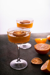 orange vodka tequila gin tonic mandarin cocktail with special cocktail glass, dried oranges kumquats on background, rear white soft light