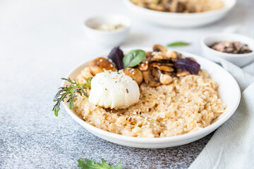 Savory porridge for breakfast. Oatmeal or spelt flakes with poached egg, fried mushrooms and herbs. Healthy food. Keto diet.