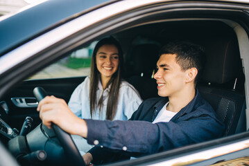 Fototapeta na wymiar Happy Young Couple Sitting Inside Their Car Enjoying Road Trip, Travel and Adventure Concept