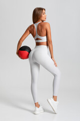 Fitness woman. Athletic girl training with medicine ball on the gray background
