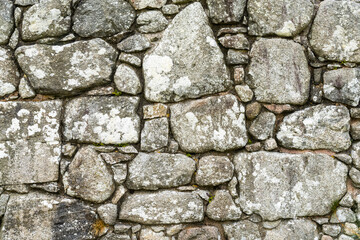 background of an old stone wall built with uneven and random blocks and stones