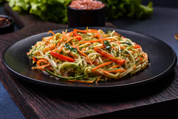 Fresh salad of sliced thin strips of carrot and zucchini on a concrete background