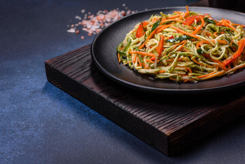 Fresh salad of sliced thin strips of carrot and zucchini on a concrete background