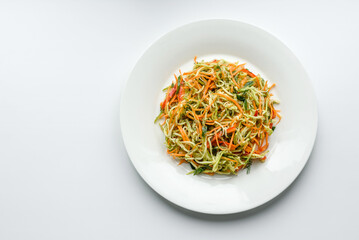 Fresh salad of sliced thin strips of carrot and zucchini on a concrete background
