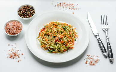 Fresh salad of sliced thin strips of carrot and zucchini on a concrete background