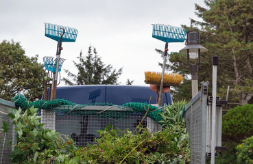 Konzept Hausmeister- und Gartenservice: Besen, Rechen, Schaufeln und andere Werkzeuge für Haus und Garten sowie Laub auf einen kleinen Transporter, Copy space