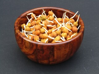 Sprouted chickpeas in a wooden bowl on black background 