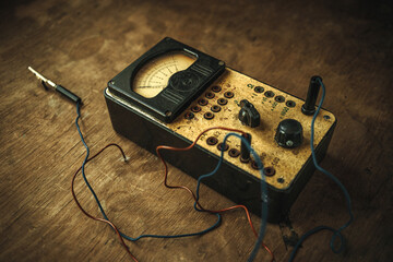 Vintage voltage measuring device. An old electrician's tool on a wooden table. Multimeter of the...