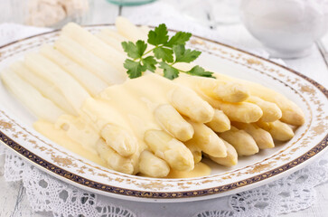 Traditional style steamed white asparagus with sauce hollandaise served as close-up on a classic...