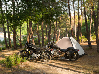 Free time activity concept. Motorcycles and tent camping. Bikers camping in the forest. It's...