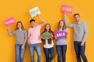 Group of young people holding speech bubbles with words HELLO in different languages on yellow...