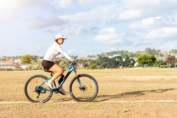 Obraz premium Young woman riding her mountain bike enjoying a sunny day in the park. High quality photo