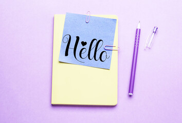 Sticky note with word HELLO and stationery on lilac background, top view